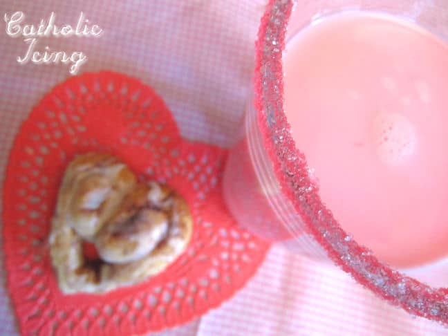 Glass of strawberry milk with pink sugar rim and heart-shaped cinnamon roll