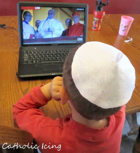 Child watching Pope Francis speech wearing a homemade Zucchetto